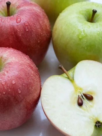 Frische rote und grüne Äpfel auf Schneidebrett, geschnitten und ganz, mit Apfelsaft