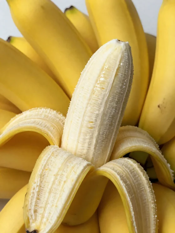 Frische Banane im Ganzen und geschnitten, in Schale und auf rustikalem Tisch