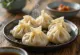 Chinesische Schweinefleisch-Jiaozi Teigtaschen gekocht, auf weißem Teller serviert