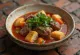 Thareed mit Räucherfleisch, serviert mit frischem Koriander und Brotwürfeln